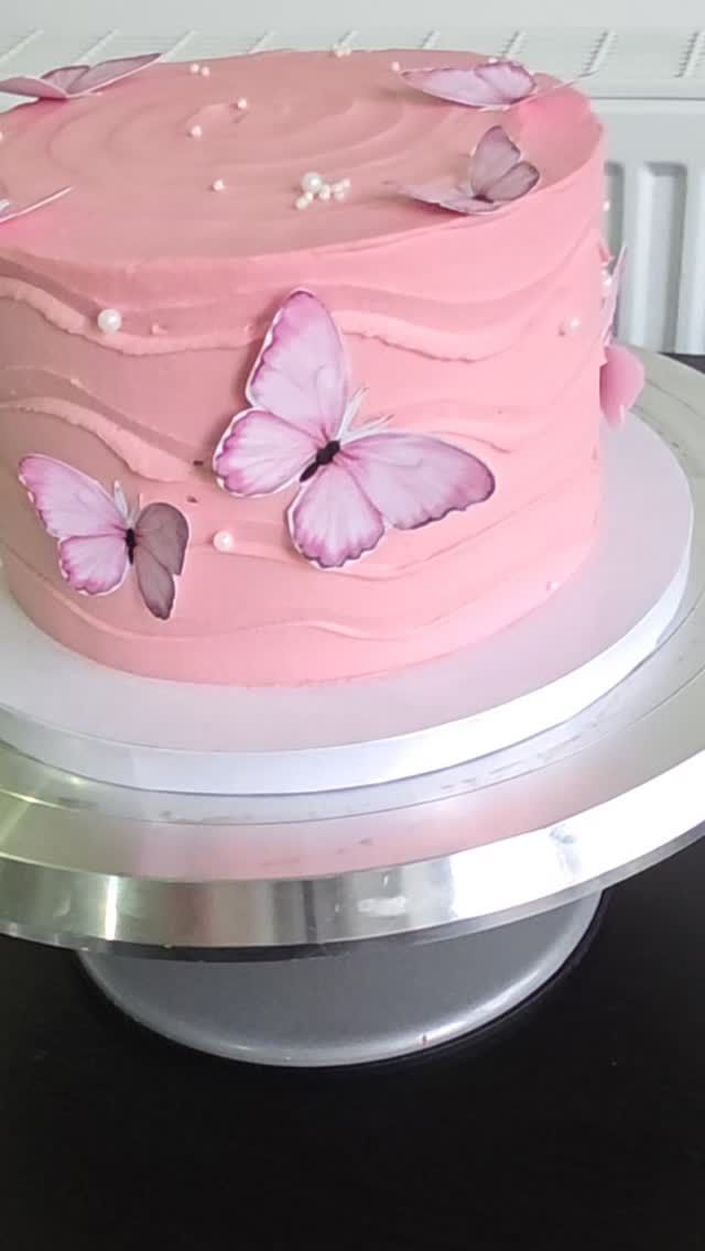 A pink buttercream birthday cake with lilac wafer butterflies